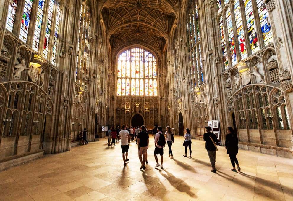 The inside of a university college church in Cambridge, with large stained glass windows