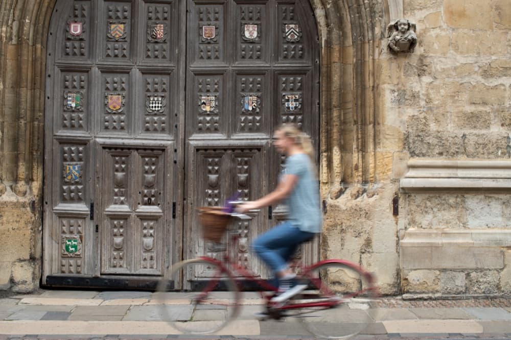 A cyclist passing an historic Oxford college entrance