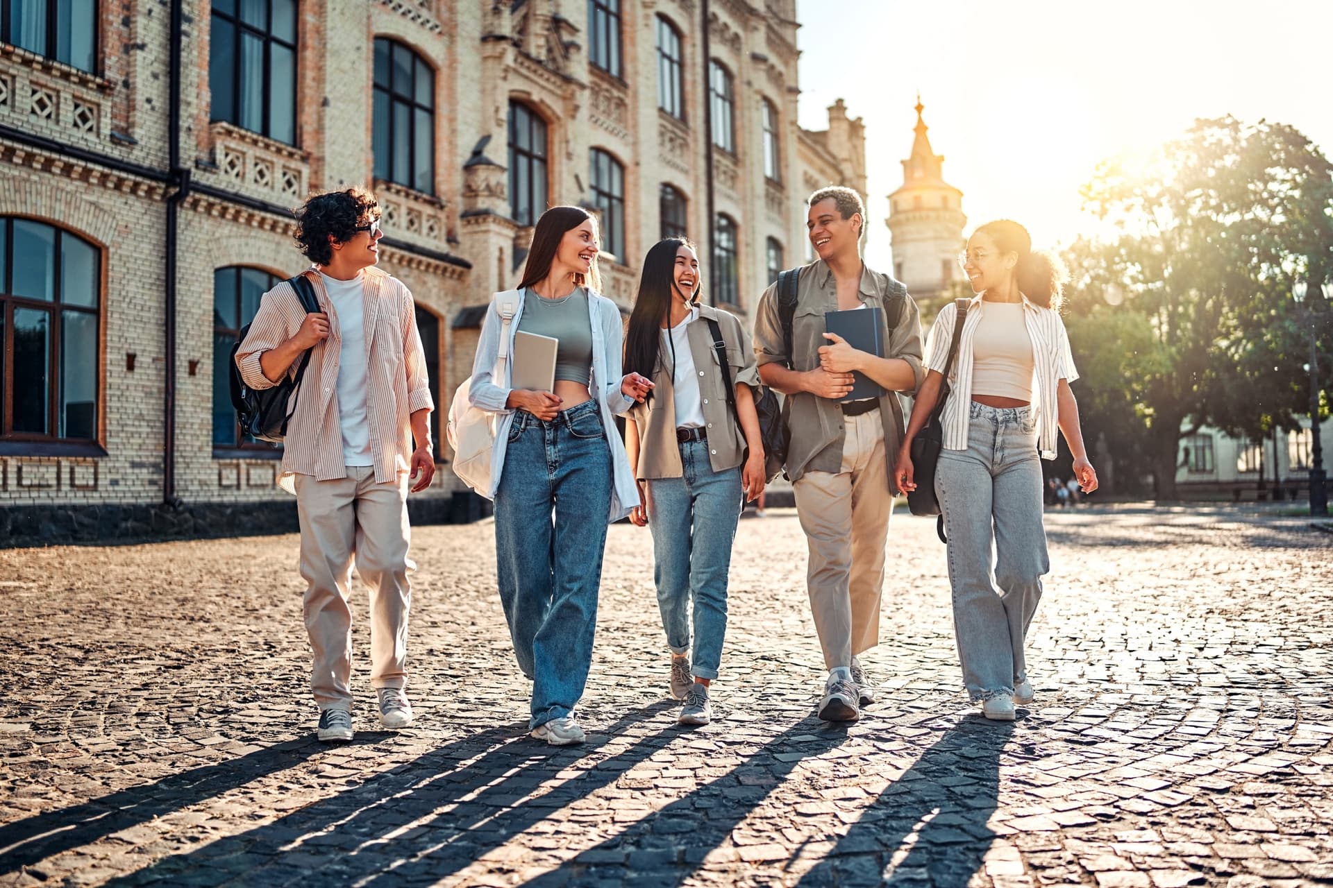 A group of smiling students walking across a sunny university campus